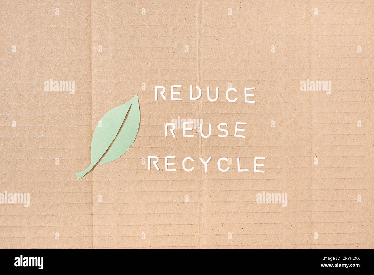 Reduce Reuse Recycle-Konzept. Blatt- und Papierstreifen mit ausgeschnittenem Text auf Papphintergrund Stockfoto