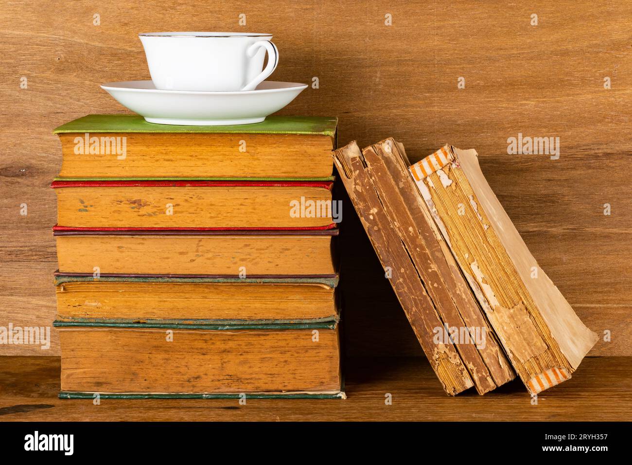 Stapel alter Bücher und eine Tasse Kaffee auf Holztisch. Stockfoto