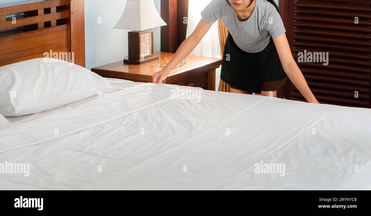 Junge professionelle Zimmermädchen machen Bett im Hotelzimmer Stockfoto