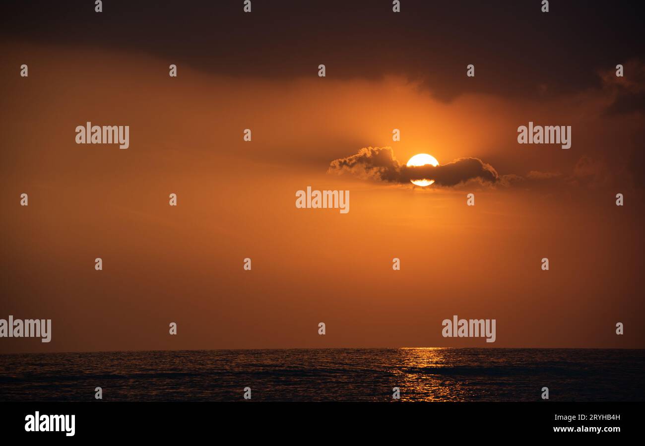 Dramatischer Sonnenuntergang über dem Meer. Bewölkter und orangener Himmel. Wunderschöner Tagesabschluss Stockfoto