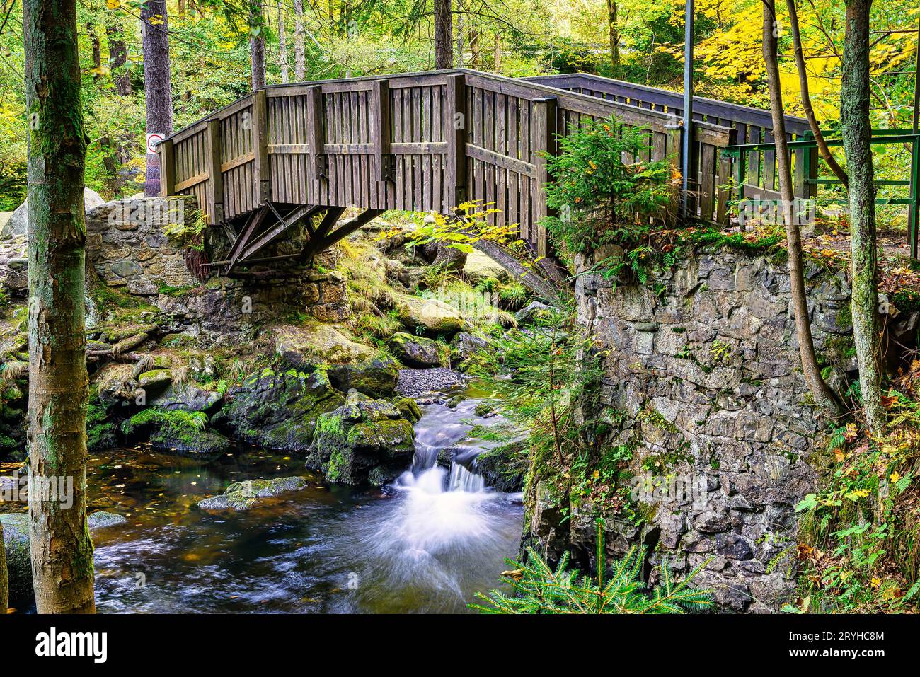 Holzbrücke über die Oker mit großen Steinen auf der Insel Engagement im Harz, Stockfoto