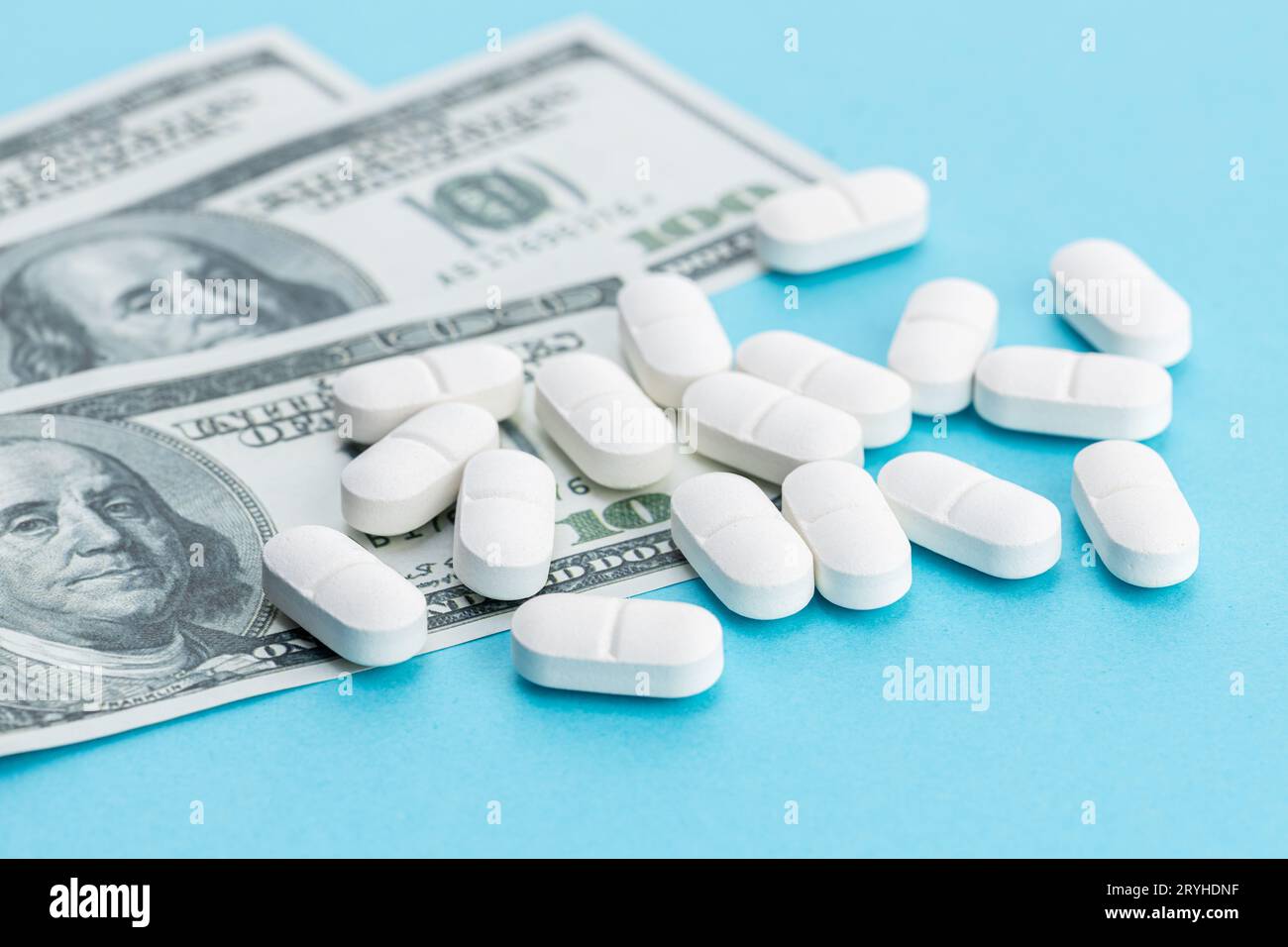 Kostenkonzept Medizin. US-Dollar-Scheine und Medizinpillen auf blauem Hintergrund Stockfoto