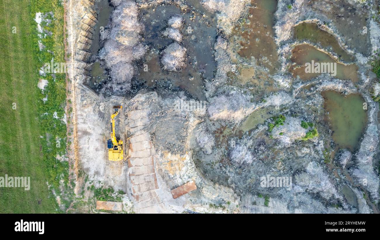 Gelber Planierschild führt Erdarbeiten durch – Luftaufnahme. Gelber Raupentraktor hake den Boden, um ein Asphaltroa zu bauen Stockfoto