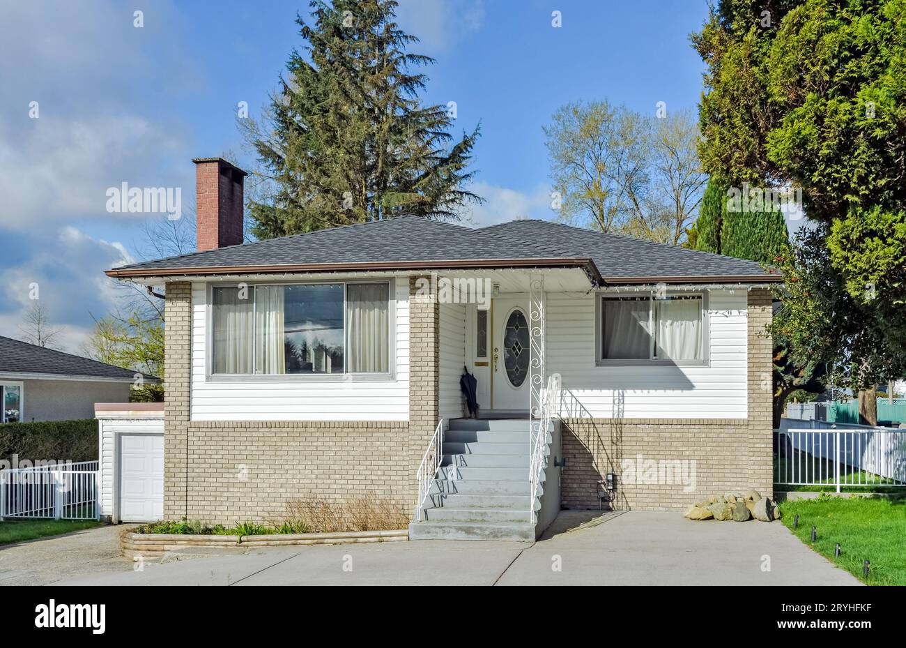 Durchschnittliches Wohnhaus mit Betontreppen und gepflastertem Vorgarten Stockfoto