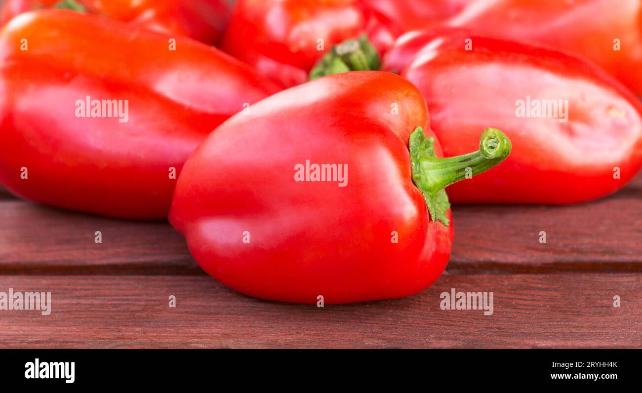 Rote Paprika auf Holztisch Nahaufnahme. Rote Paprika in einem Stapel Stockfoto