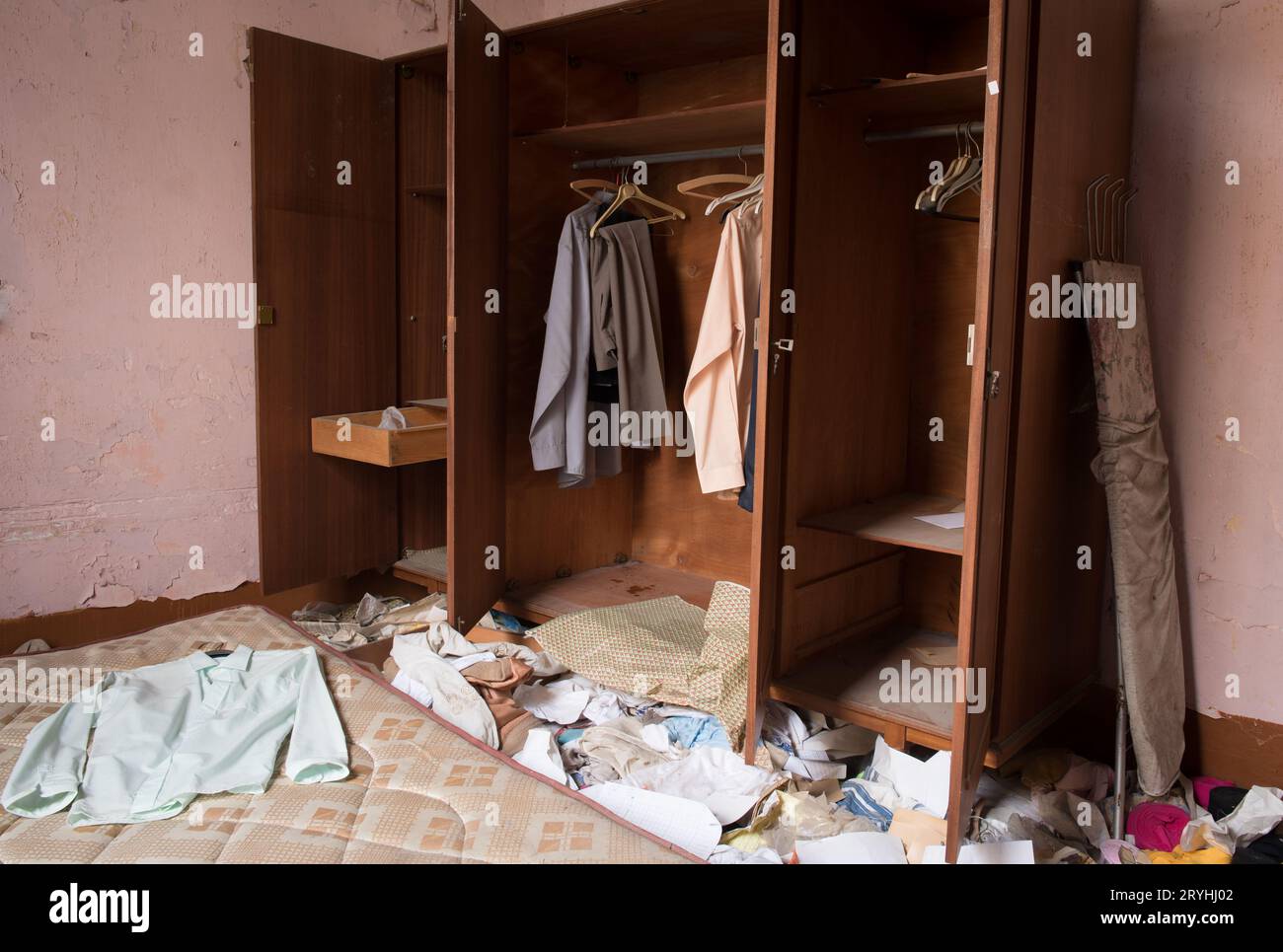 Verlassenes, dreckiges Schlafzimmer mit alten, gebrauchten Kleidern auf dem Boden und auf den Kleiderschränken Stockfoto