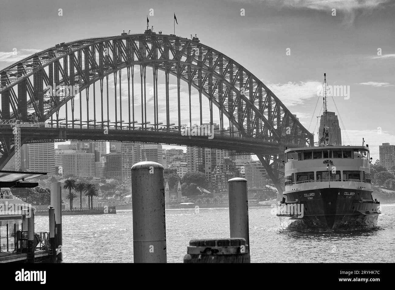 Schwarzweiß-Foto der berühmten Manly Ferry, MV COLLAROY, die sich der Wharf am Circular Quay nähert, im Hintergrund die historische Sydney Harbour Bridge Stockfoto