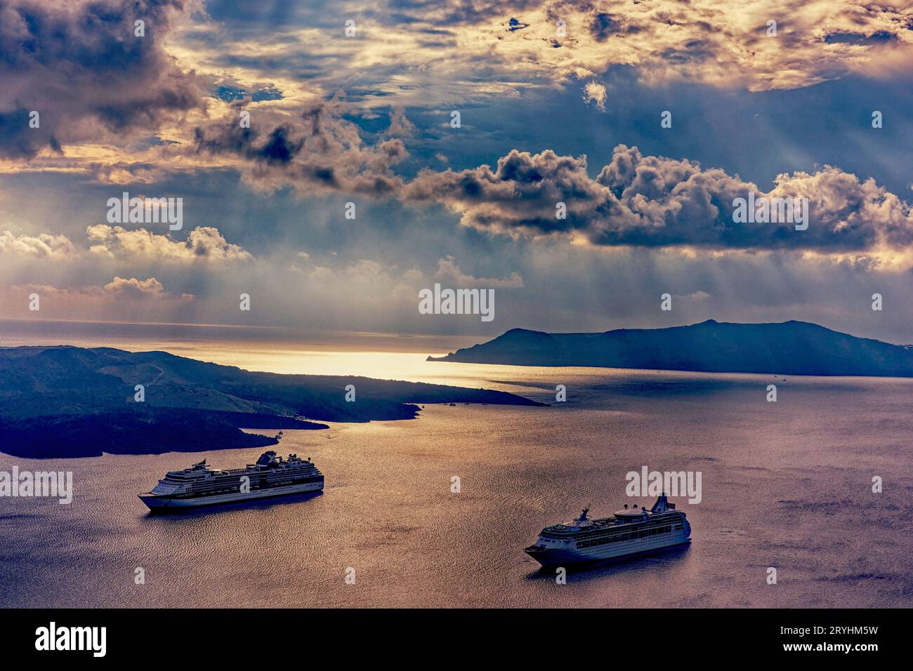 Hafen von Santorin in goldenem Licht mit vor Anker liegenden Kreuzfahrtschiffen Stockfoto