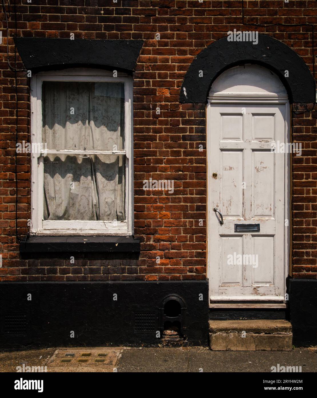 Das traditionelle britische Dorf beherbergt Außenfassaden mit geschlossener Tür und Fenster an einer Steinmauer Stockfoto