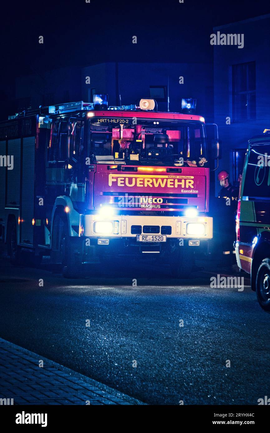 Vertikaler Schuss eines roten deutschen Feuerwehrautos im Nachtbetrieb Stockfoto