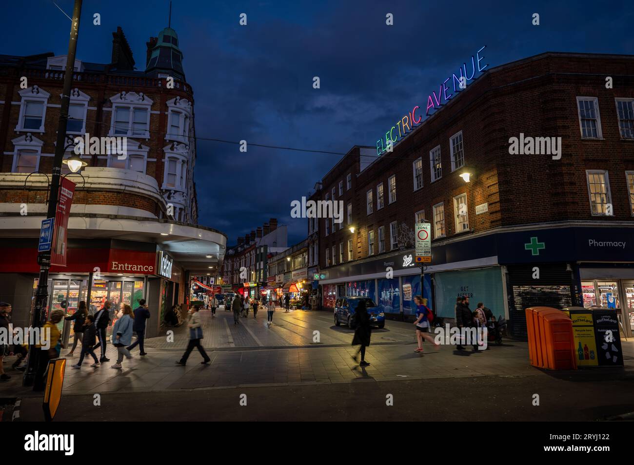 Brixton, London, Großbritannien: Electric Avenue in Brixton bei Nacht. Von der Brixton Road mit dem farbenfrohen Neonschild Electric Avenue aus gesehen. Stockfoto