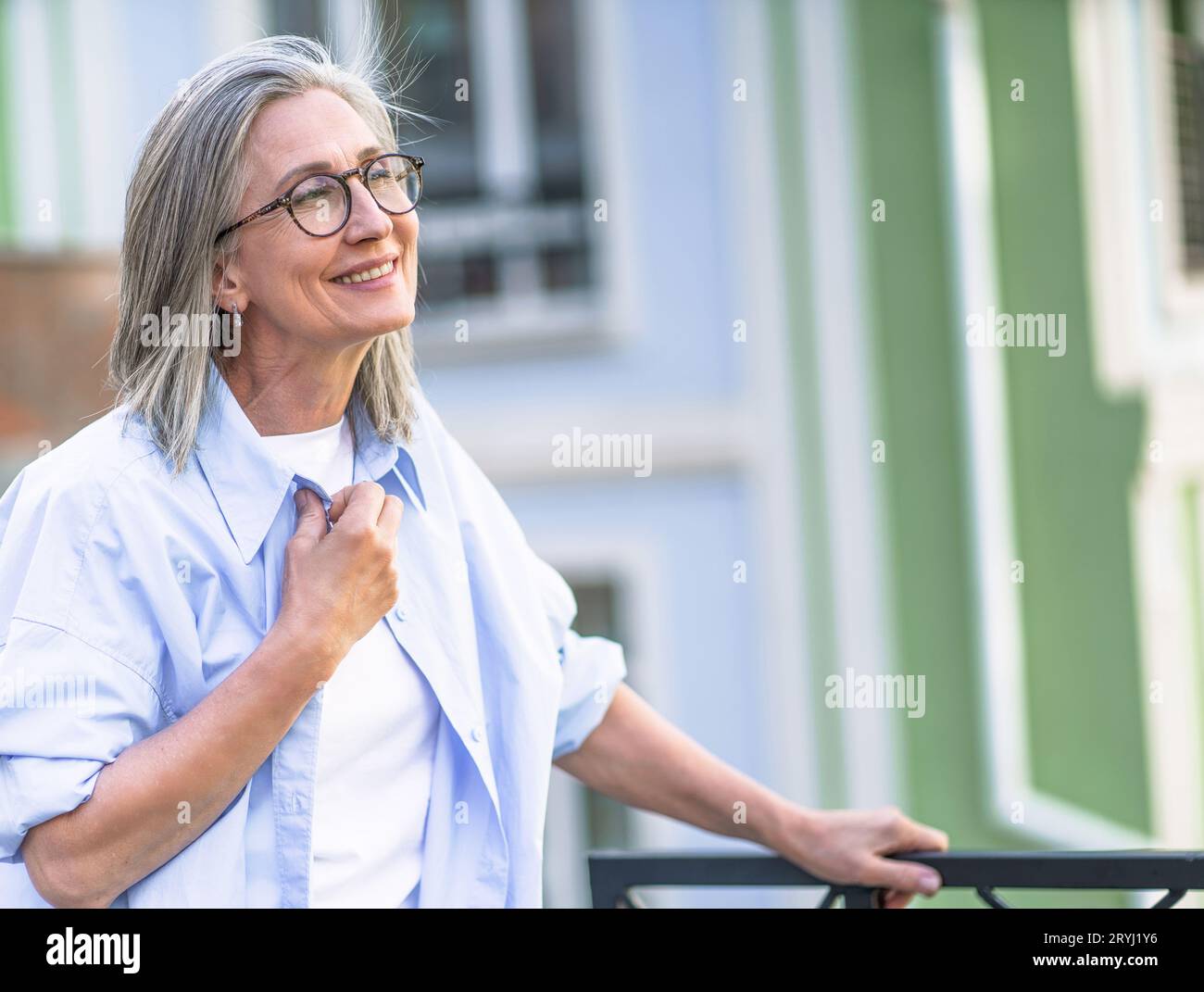 Glücksvorstellung mit einer Seniorin, die mit geschlossenen Augen lächelt, in der Altstadt. Fröhliche Frau, die das Stadtbild genießt, im Freien, Reisen, Stockfoto