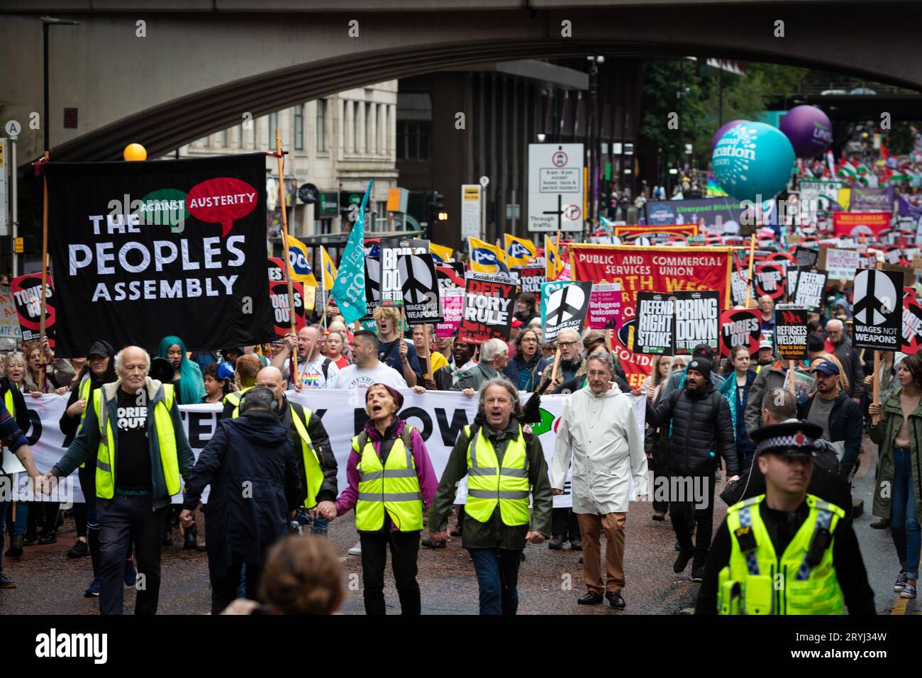 Manchester, Großbritannien. Oktober 2023. Demonstranten mit spruchbändern marschieren auf die Konferenz zu. Tausende von Menschen marschieren während der Konservativen Partei-Konferenz durch die Stadt, um eine nationale Demonstration durchzuführen. Die Forderungen, die von der Volksversammlung organisiert und von Gewerkschaften unterstützt werden, umfassen die Beendigung der Lebenshaltungskrise und die Verteidigung des NHS. Andy Barton/Alamy Live News Stockfoto