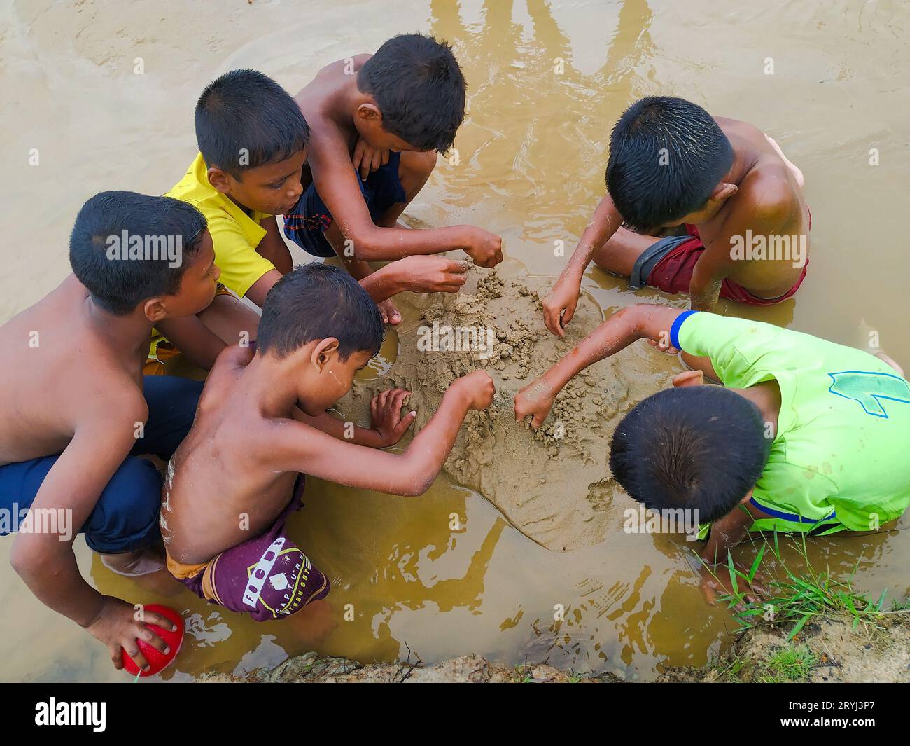 Rohingya Flüchtlingskind spielt und markiert Sandhaus Stockfoto