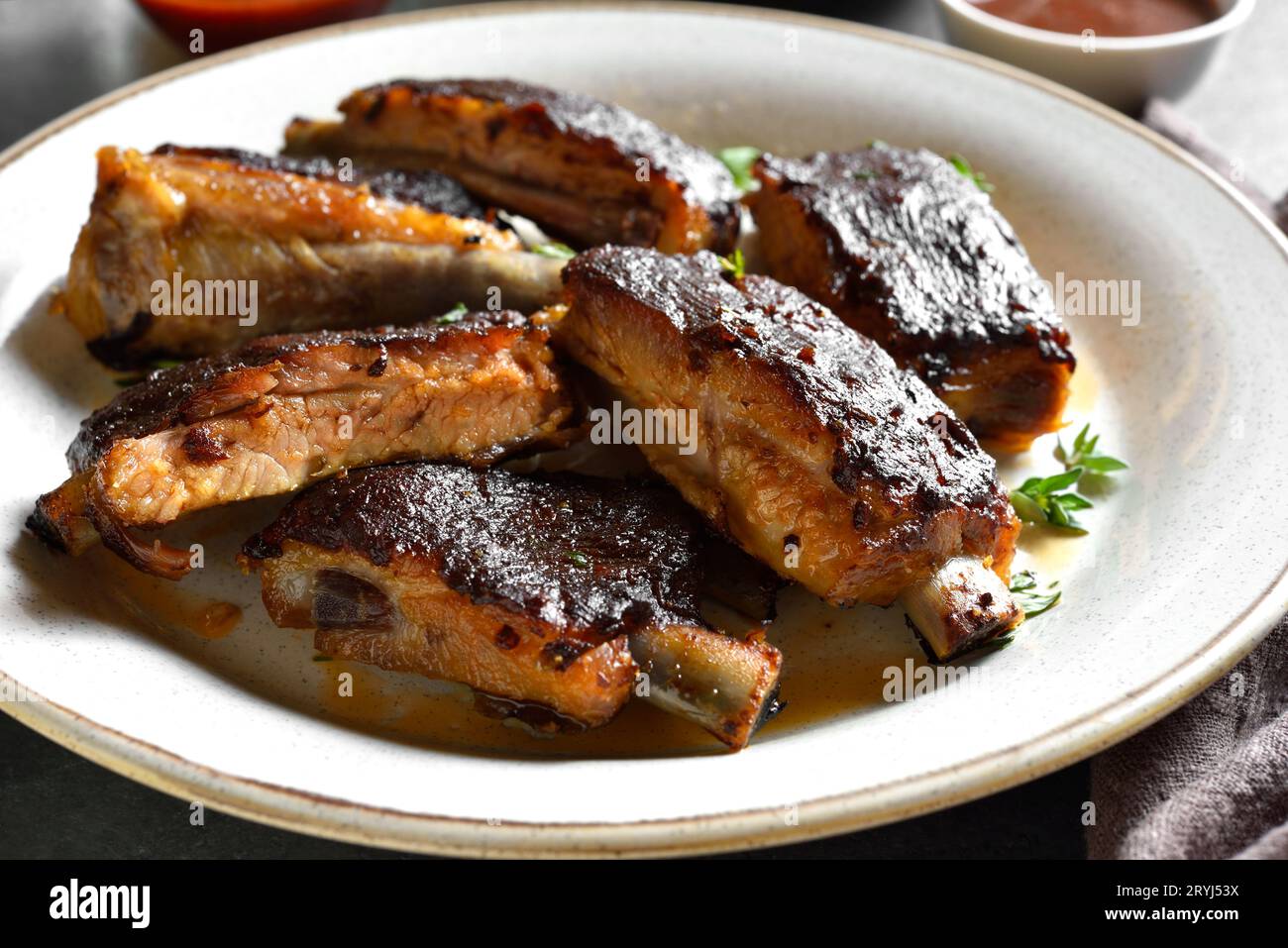Nahaufnahme von geschnittenen Schweinerippchen auf weißem Teller. Stockfoto