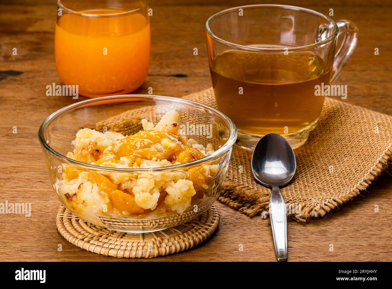 Köstlicher hausgemachter Pfirsichschuster in transparenter Glasschale auf Bambusmatte. Stockfoto