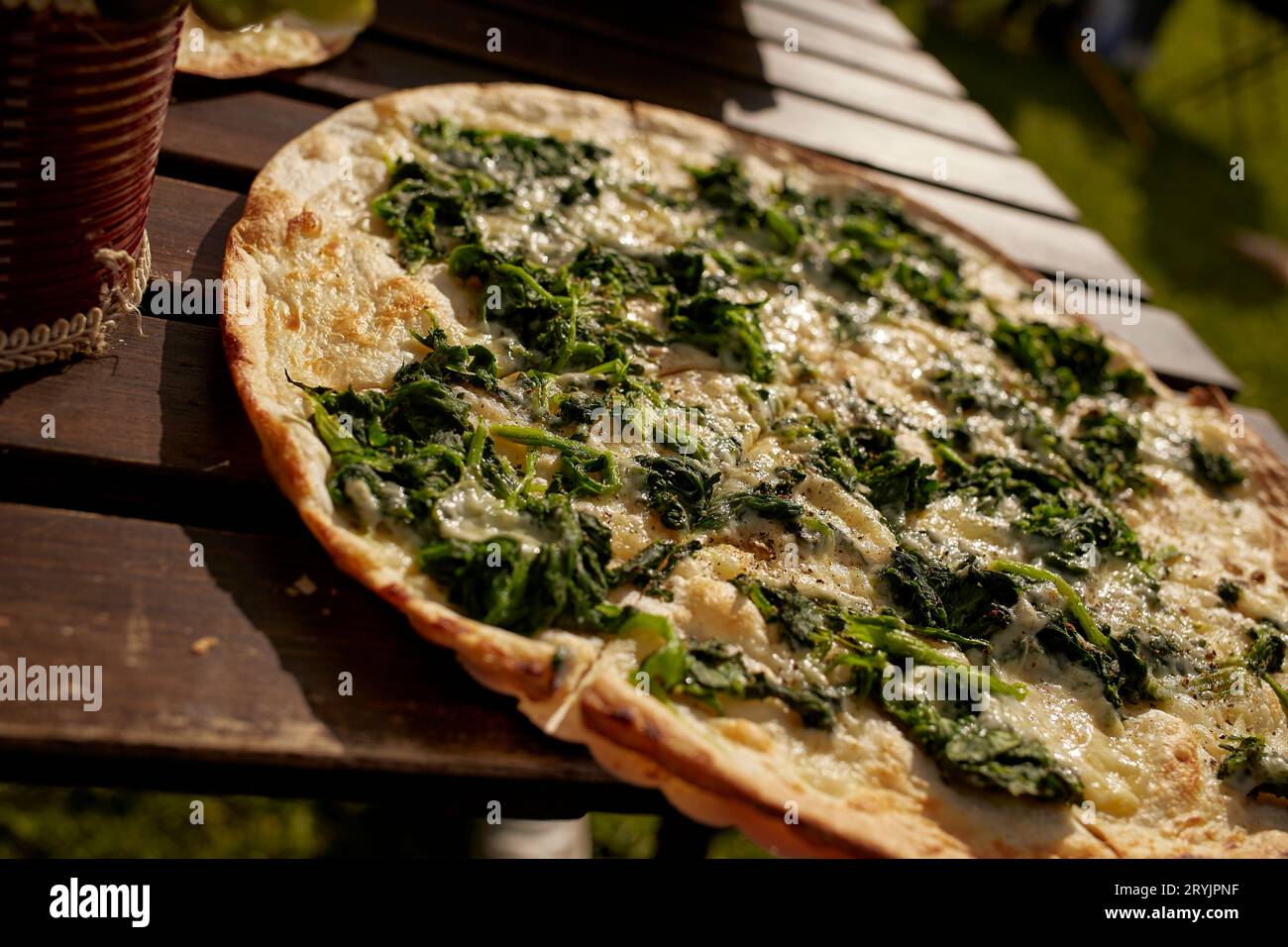 Elsässische Flammkuchen mit Spinat und Käse auf einem Tisch in einem Biergarten-Restaurant Stockfoto