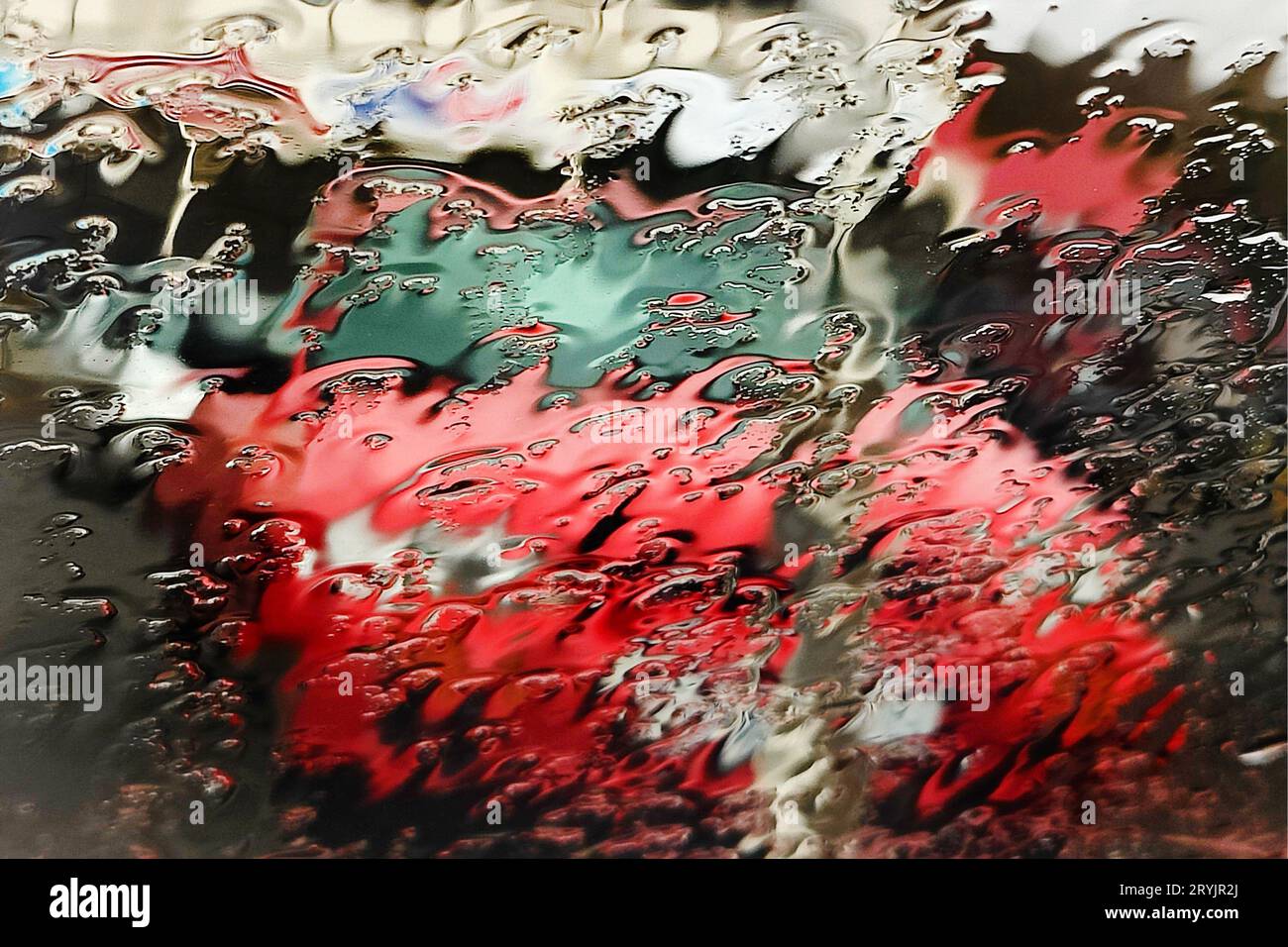 Verschwommener Blick aus dem Auto durch ein regengetränktes Fenster auf einem roten Auto, Island Stockfoto