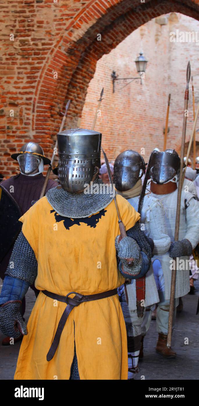 Mittelalterlicher Ritter mit gelber Tunika und Rüstung und schützendem Metallhelm auf dem Kopf während einer historischen Nachstellung Stockfoto