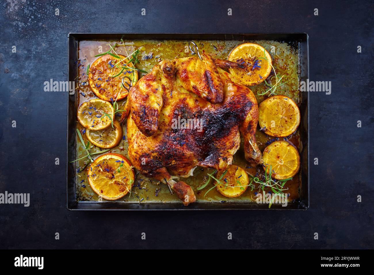 Traditionelles gegrilltes Hühnchen al-Mattone-Chili mit Orangenscheiben und Kräutern, serviert als Draufsicht auf einem alten rustikalen Meta Stockfoto