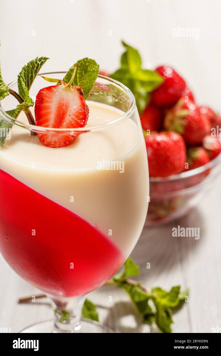Kirsch- und Milchgelee im Glas, dekoriert mit Minzblättern. Stockfoto