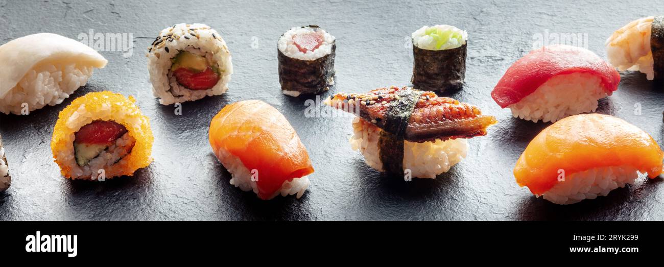 Sushi-Panorama. Nigiri mit Aal, Lachs und Thunfisch, Brötchen mit Avocado usw. Stockfoto