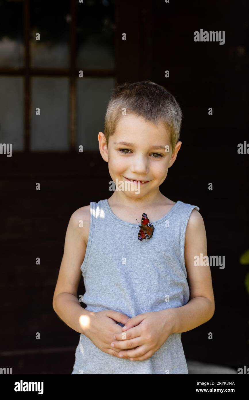 Ein Schmetterling sitzt auf einem Jungen. Im Dorf im Sommer, Sommerferien. Stockfoto