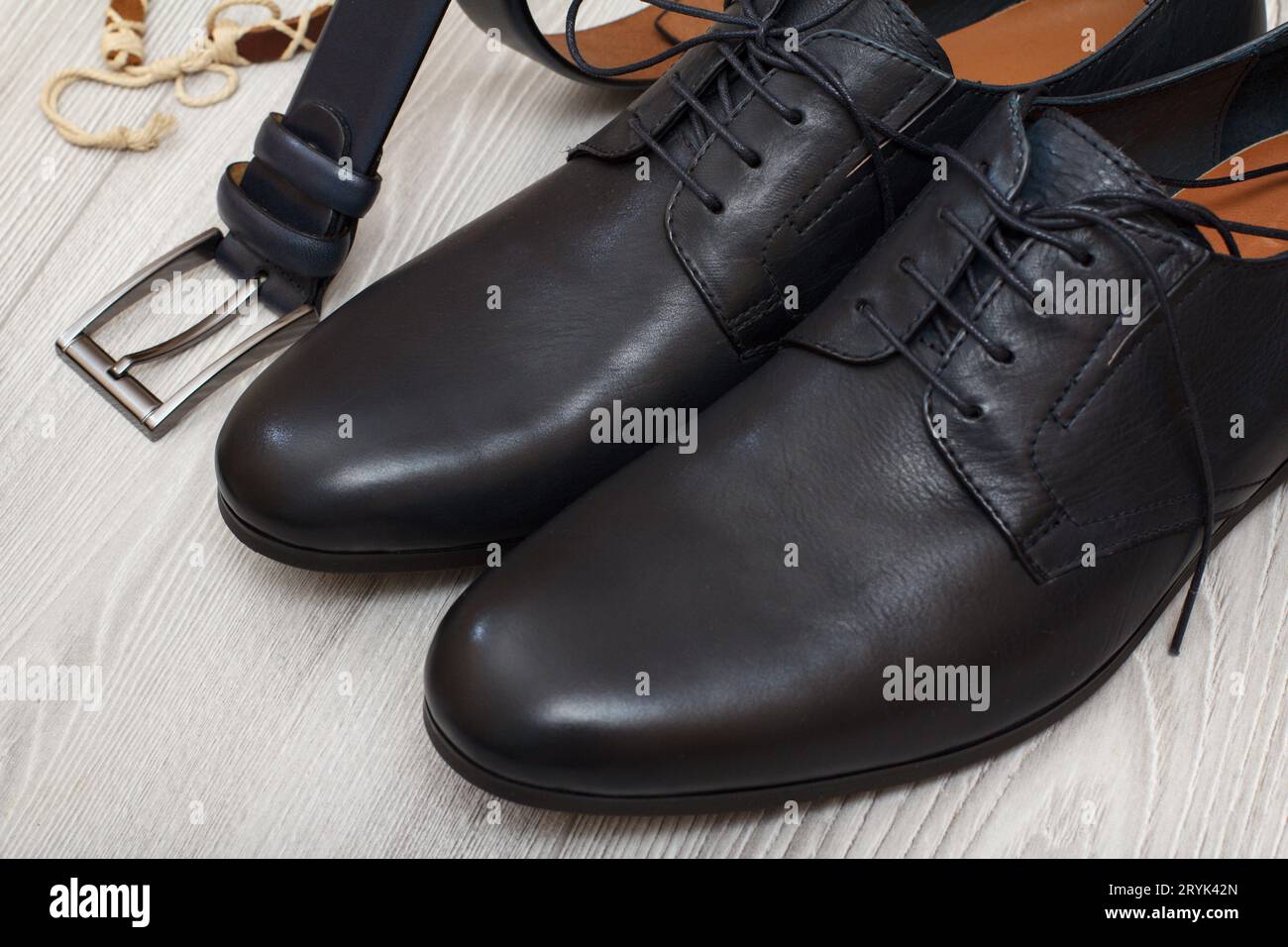 Paar schwarze Lederschuhe für Herren und Ledergürtel für Männer auf dem Boden. Stockfoto