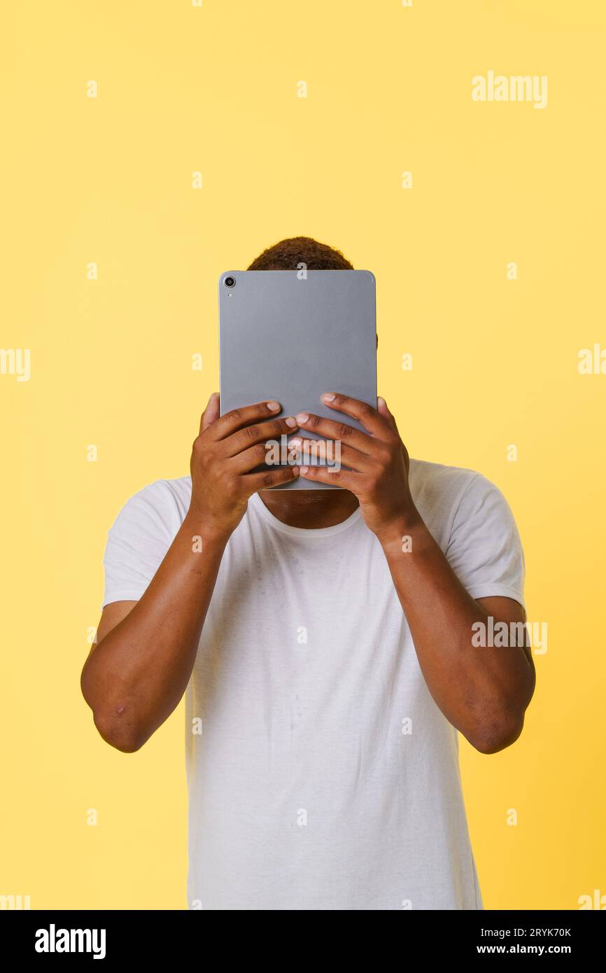 Anonymität Inkognito Online-Konzept. Anonyme afroamerikanische Person, die den Tablet-PC in der Hand hält, mit verstecktem Gesicht auf b Stockfoto