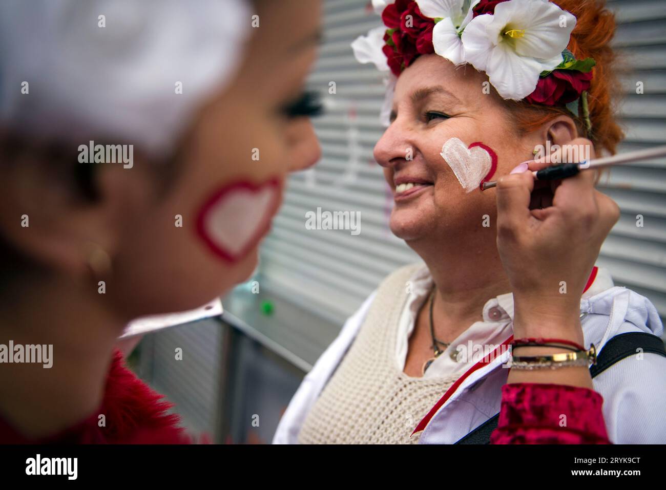 Ein rot-weißes Herz wird während des Millionen-Herzen-Märsches in Warschau auf das Gesicht einer Frau gemalt. Hunderttausende Menschen nahmen unter dem Motto "Million Hearts March" an einem Marsch in Warschau Teil, der vom polnischen Oppositionsführer Donald Tusk organisiert wurde. der sich in seinen Bemühungen, die nationalistisch-konservative Regierung bei den bevorstehenden Parlamentswahlen am 15. Oktober zu entlasten, einem heftigen Kampf gegenübersieht. Der marsch, die größte Wahlkampfveranstaltung der Oppositionskoalition, war inspiriert von dem großen Erfolg eines ähnlichen marsches am 4. Juni, der Hunderttausende von Oppositionellen an sich zog Stockfoto