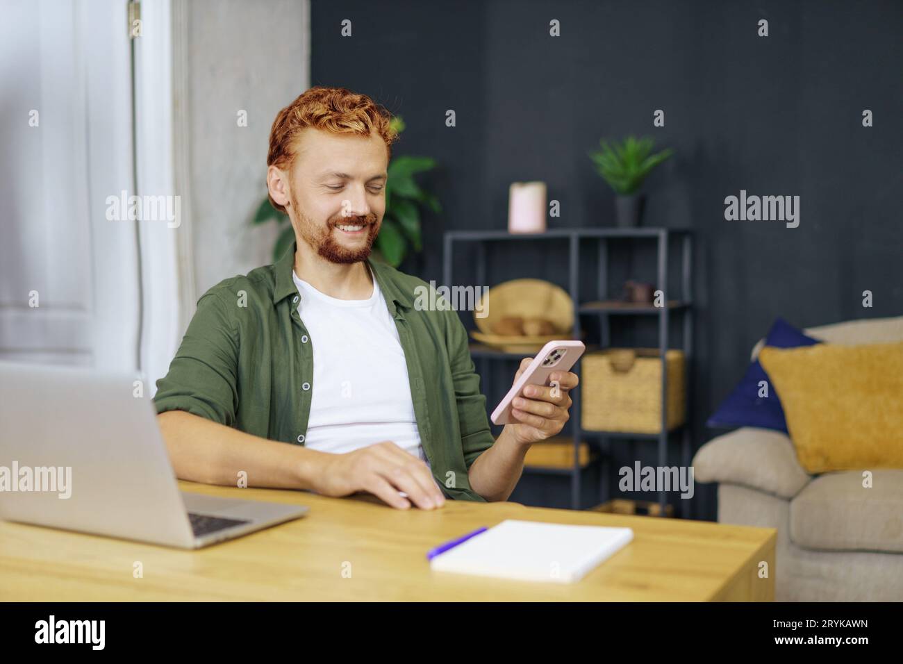 Programmierer Mann mit rotem Fuchshaar, sitzt am Schreibtisch in einem gemütlichen Innenraum. Er arbeitete an einem Laptop und betonte das Konzept von Fre Stockfoto