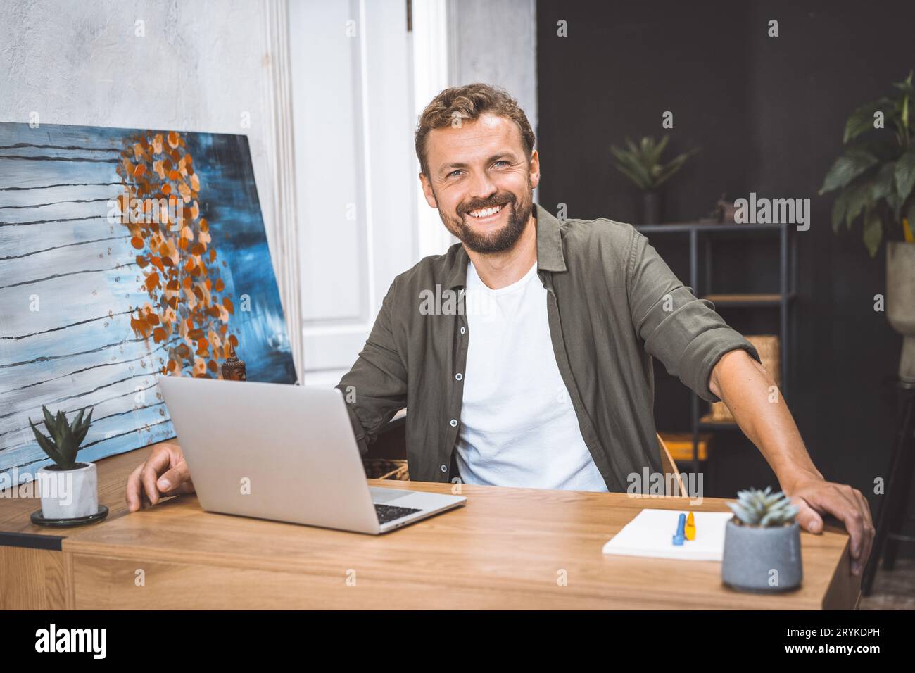 Konzept von Fernarbeit, freiberuflicher Tätigkeit und Produktivität im digitalen Zeitalter. Fröhlicher und produktiver Mann, arbeitet von zu Hause aus, er lächelt Stockfoto