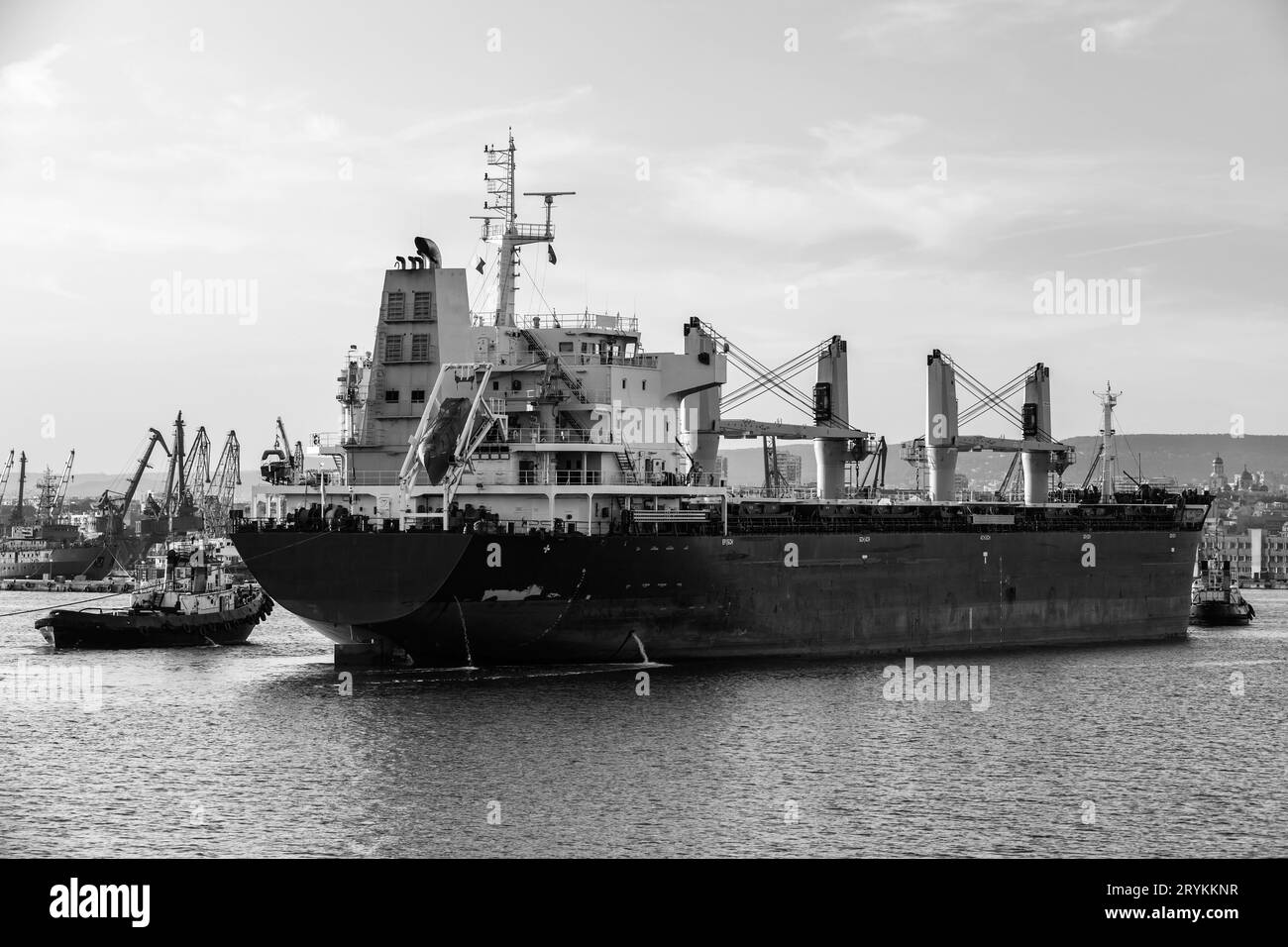 Massengutfrachter und Schlepper fahren in den Hafen von Varna, Bulgarien. Schwarzweißfoto Stockfoto