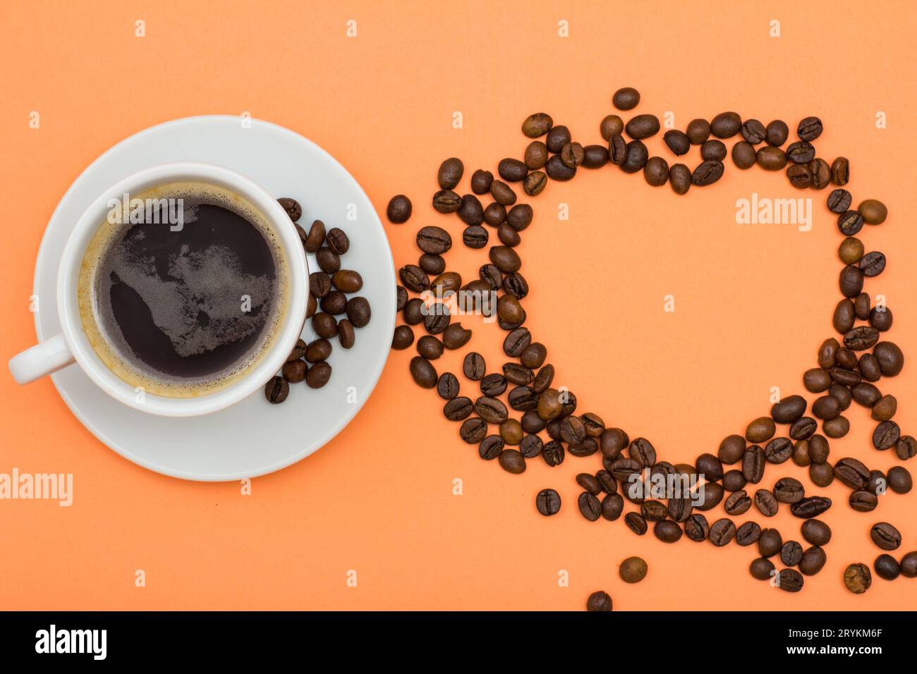 Eine Tasse Kaffee auf einer Untertasse mit Kaffeebohnen, die in Form eines Herzens gefaltet sind Stockfoto