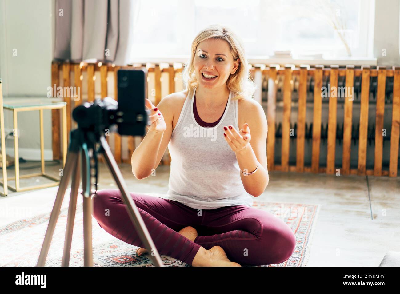 Sportliche Fitness- und Yoga-Bloggerin in Sportswear, die während des Trainings zu Hause Video vom Training auf dem Handy aufzeichnet. Stockfoto