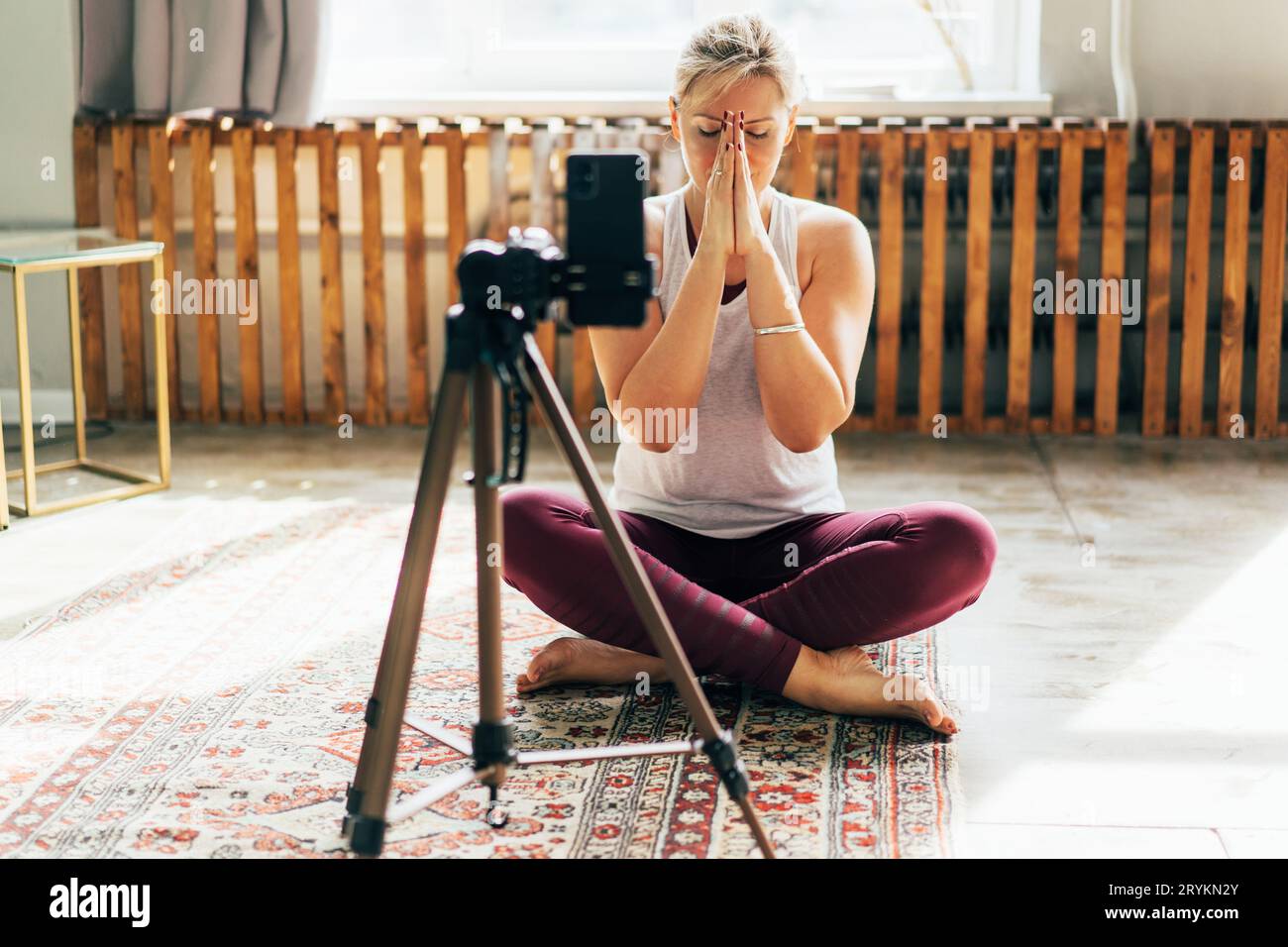 Eine Yogi-Frau zeichnet eine Meditationsstunde auf einer Handykamera auf. Stockfoto