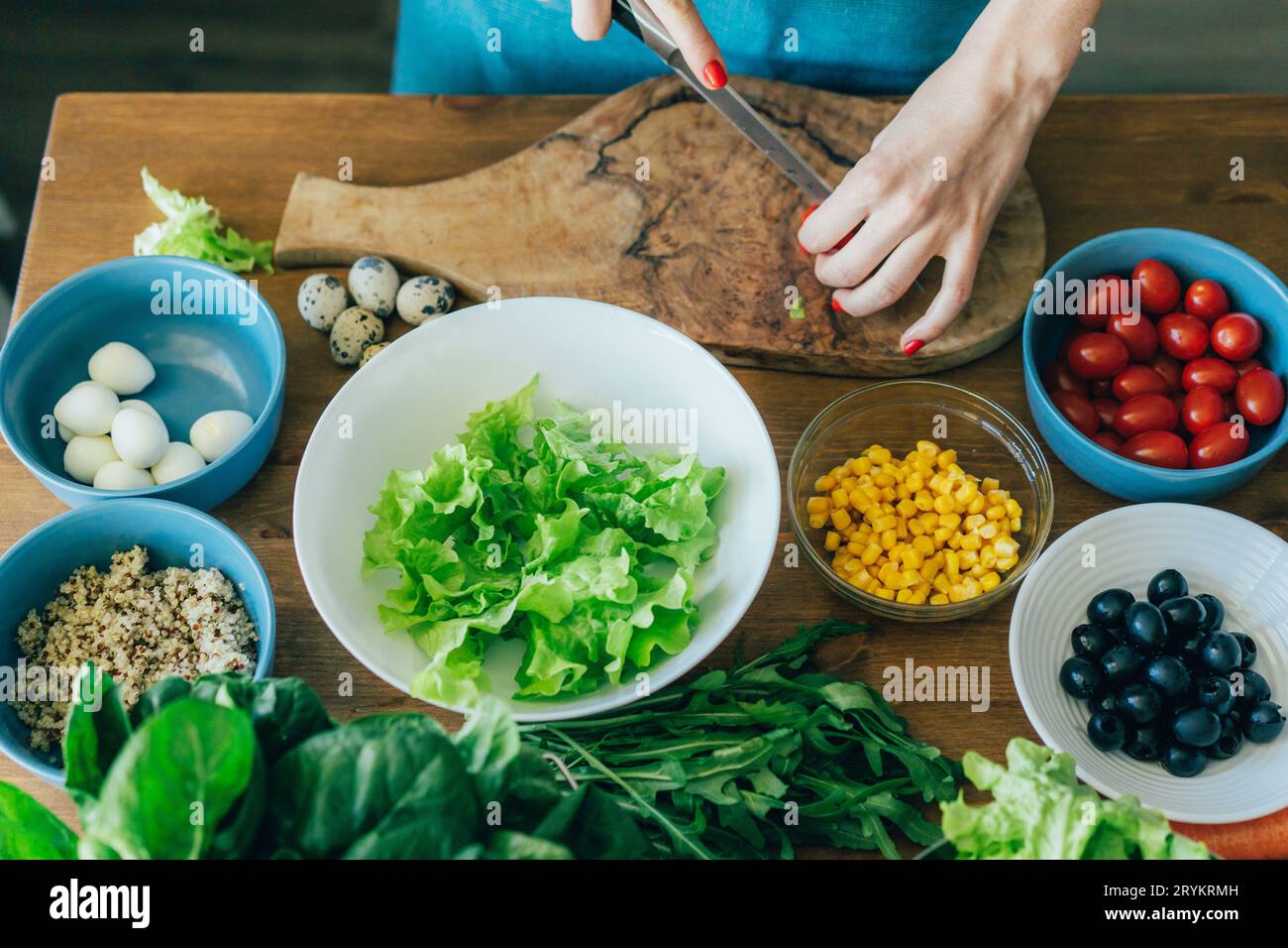 Frau schneidet Gemüse für Salat auf einem Schneidebrett. Kochen zu Hause. Stockfoto