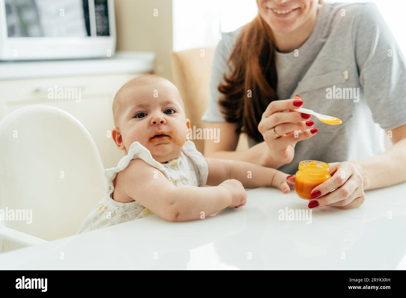 Das Gesicht eines zufriedenen Kindes, das Gemüsepüree aus einem Löffel isst Stockfoto