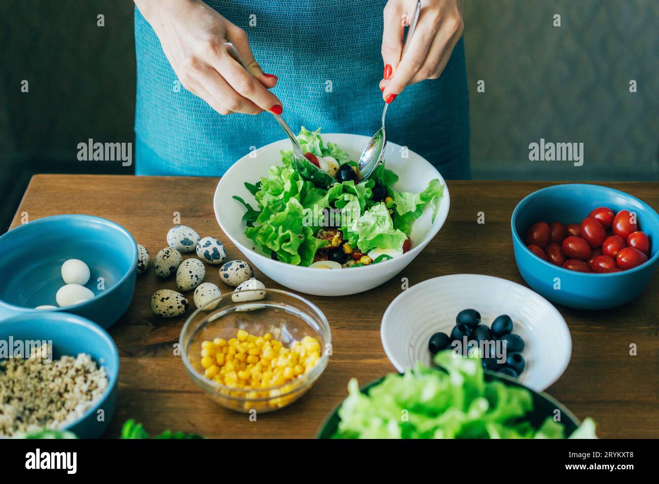 Nahaufnahme einer Frau, die grünen Salat in einer großen Schüssel mischt. Stockfoto