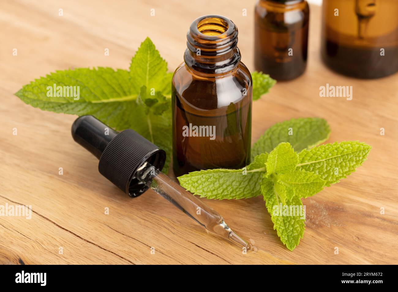 Bernsteinflasche mit ätherischem Pfefferminzöl und Tropfer auf Holztisch Stockfoto