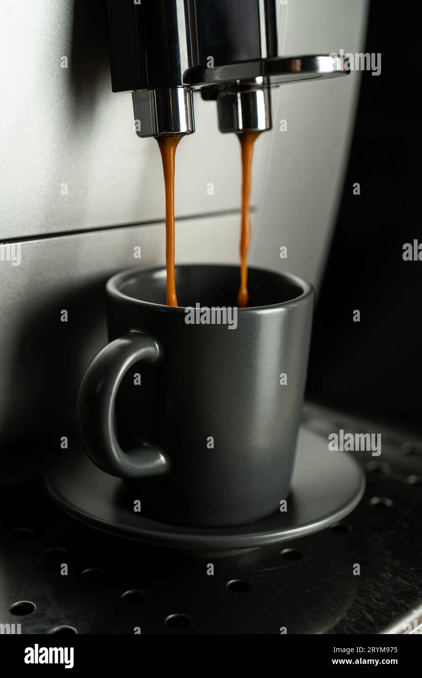 Espresso wird aus einer Kaffeemaschine zu Hause in eine Espressomaschine gegossen. Stockfoto