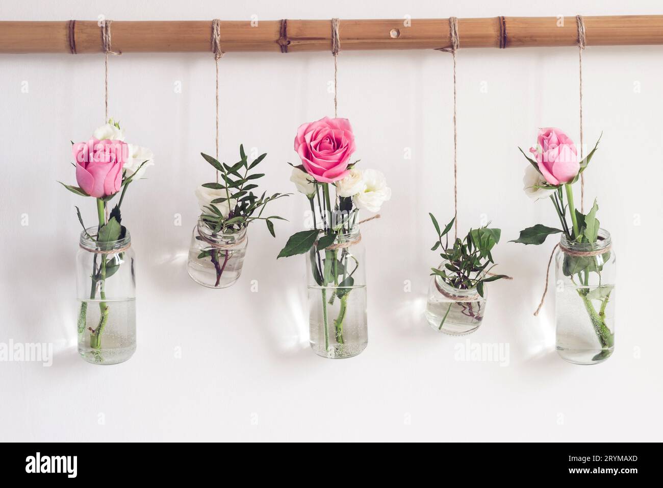 Verwenden Sie Glasgläser für die Inneneinrichtung. Vertikaler Wassergarten mit hängenden Blumen an weißer Wand. Feng Shui-Elemente Stockfoto