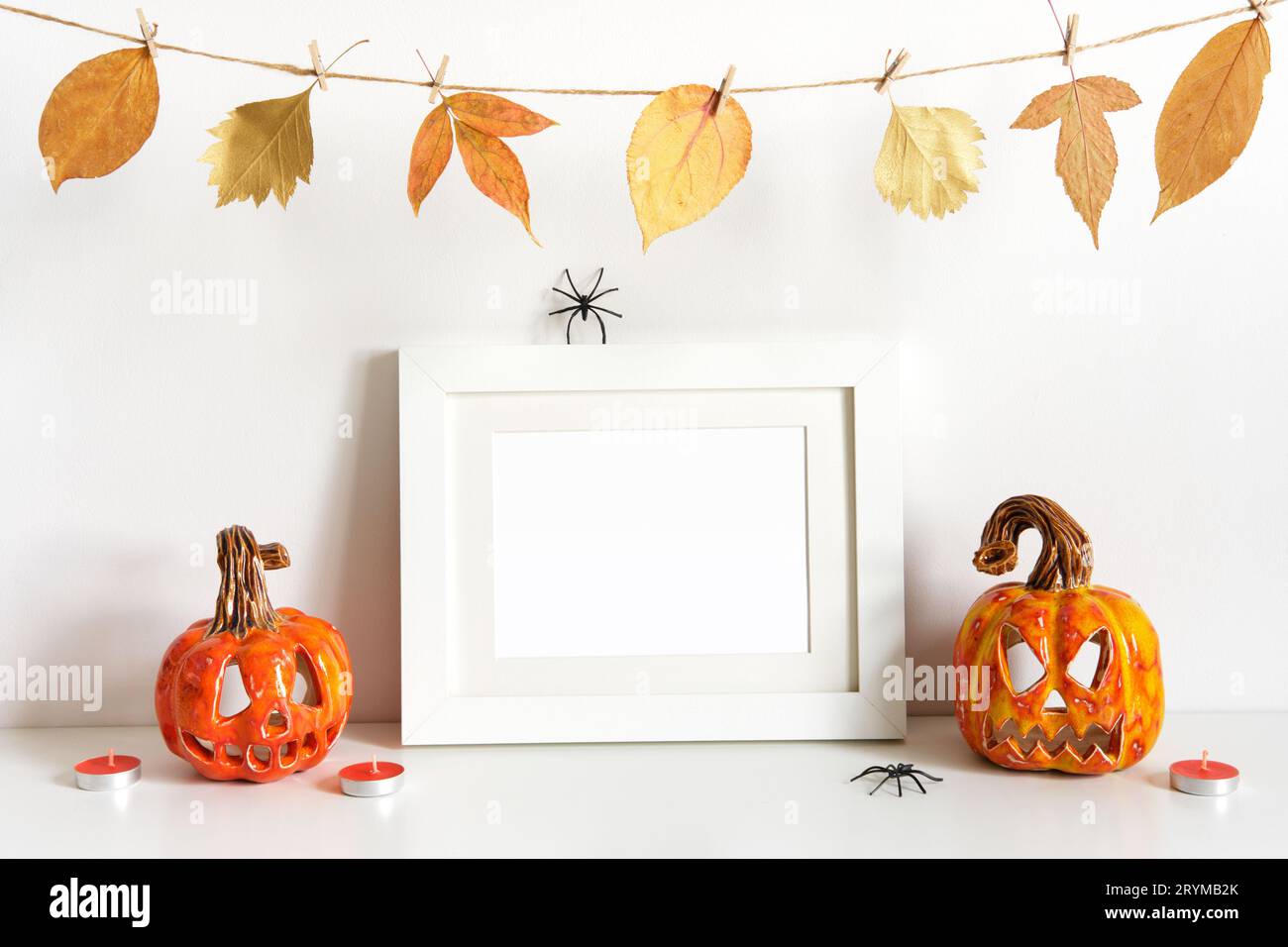 Halloween Komposition mit Keramik Kürbisse, florale Girlande und Rahmen auf Tischwand Hintergrund. Grußkartenvorlage Stockfoto