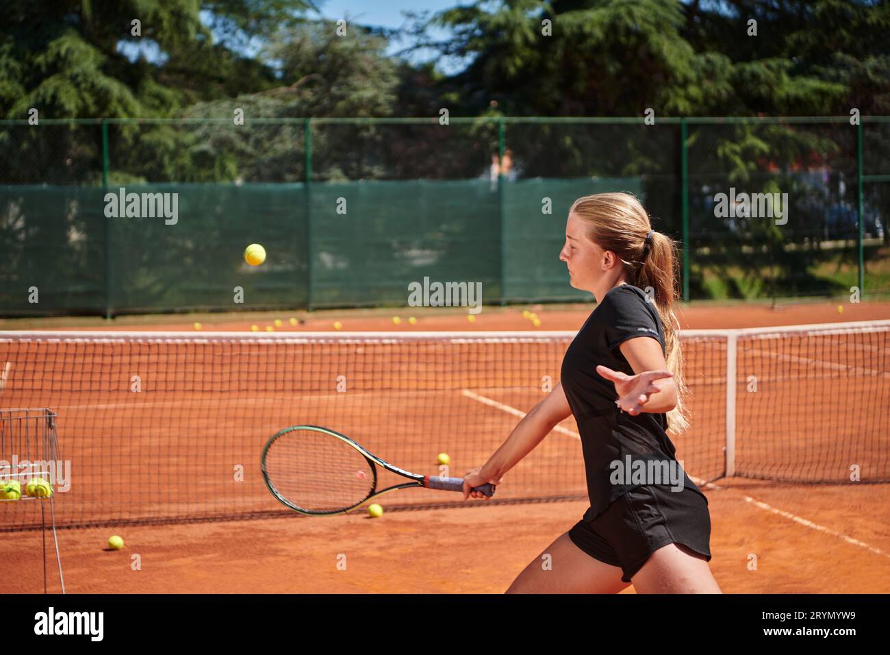 Ein junges Mädchen, das professionelle Tennisfähigkeiten in einem Wettkampf an einem sonnigen Tag zeigt, umgeben von der modernen Ästhetik von A Stockfoto