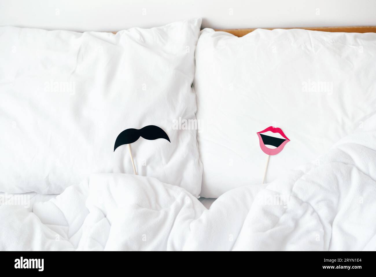 Requisiten mit Lippen für Frauen und Schnurrbart für Männer für eine Stockparty liegen auf den Kissen. Inhalte für Flitterwochen und Liebhaber von Val Stockfoto