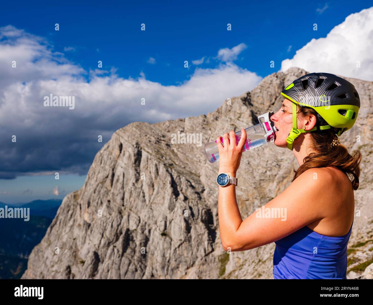 Junge Frau mit Kletterhelm trinkt aus einer Flasche im Freien, Nationalpark Gesaeuse, Admont, Steiermark, Österreich Stockfoto