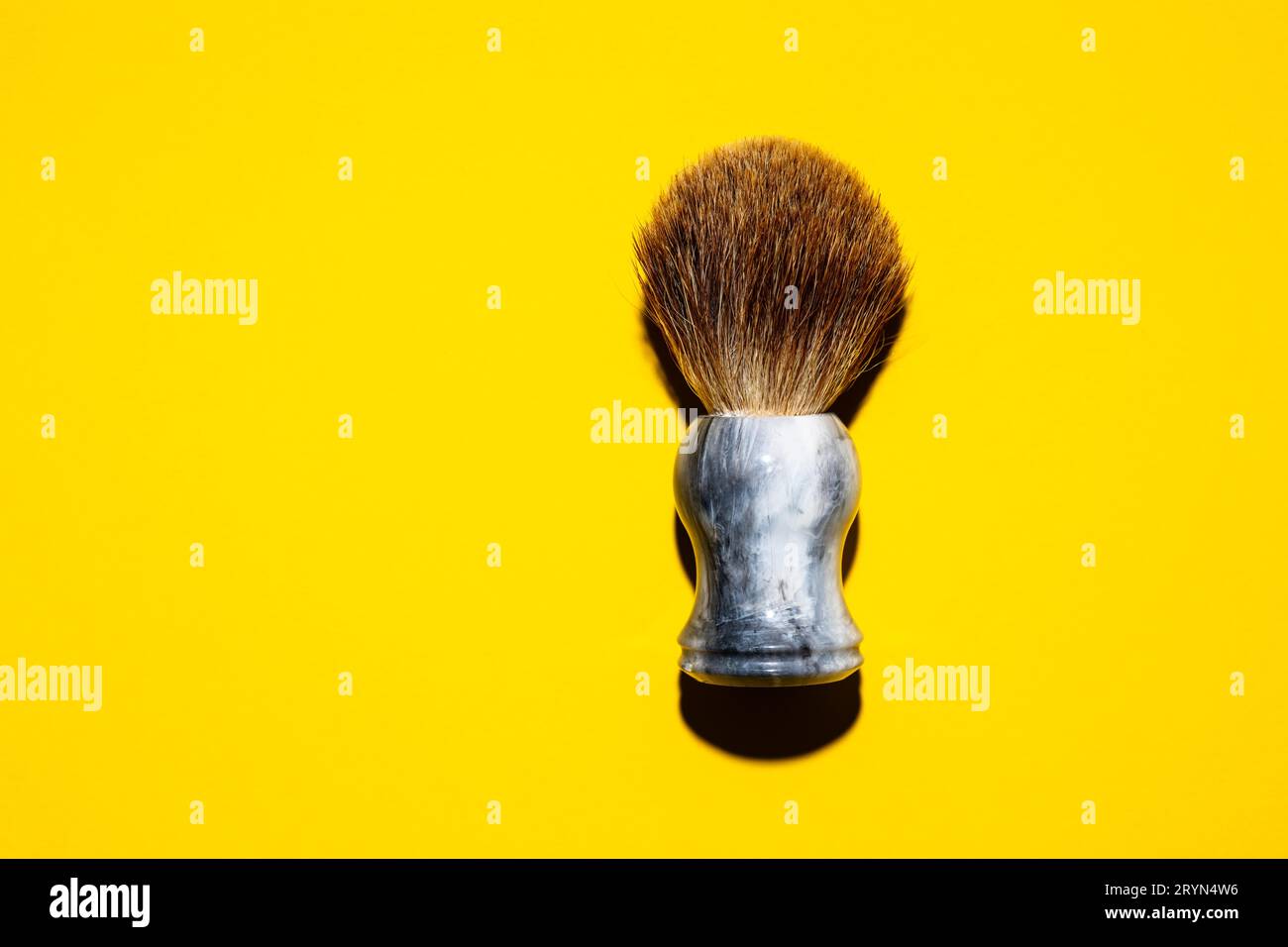 Draufsicht auf einen Rasierpinsel vor einem gelben Hintergrund Stockfoto