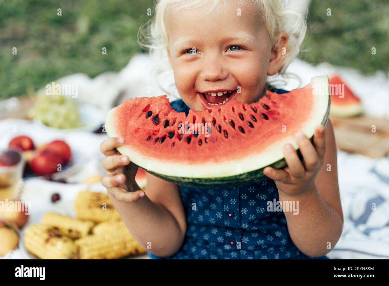 Niedliches Mädchen, das Wassermelone bei einem Picknick draußen im Sommer isst. Zeit im Vergnügen verbringen. Die unmittelbaren Emotionen von Kindern. In Stockfoto