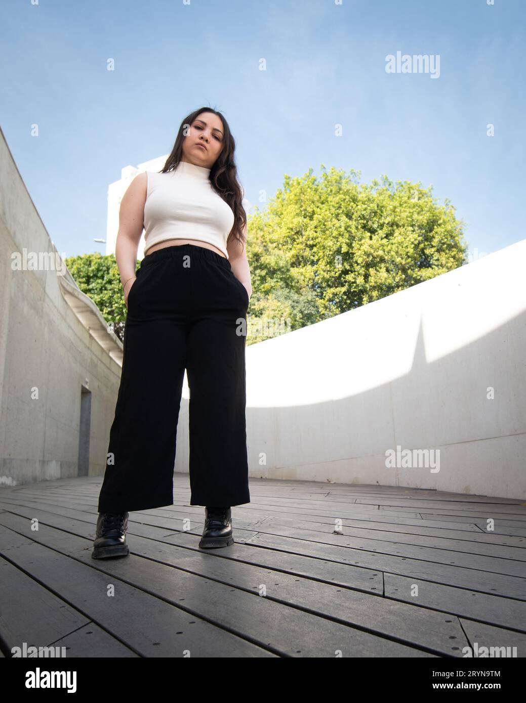 Junge attraktive Frau, die lässige Kleidung trägt und draußen in der Stadt posiert Stockfoto