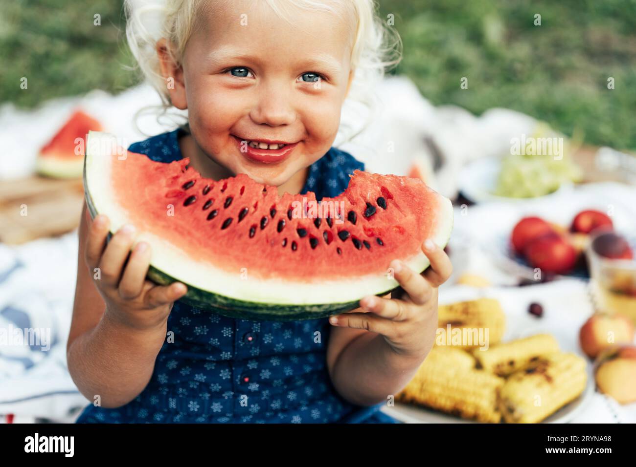 Kleines blondes Mädchen, das einen großen Wassermelonenschleim hält und Spaß hat Stockfoto